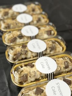 four plastic containers filled with desserts on top of a black cloth covered tablecloth