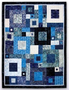 a blue and black patchwork quilt with squares on the front, one block in the middle