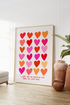 a framed art print with hearts on it in front of a couch and potted plant