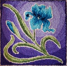 a blue flower is in the middle of a purple and green design on a piece of cloth