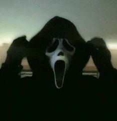 a person wearing a scream mask with their hands on their head and mouth wide open