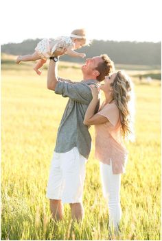 a man and woman holding a baby in a field