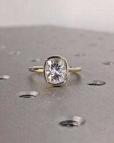 a close up of a ring with a diamond in it on a metal surface surrounded by small dots