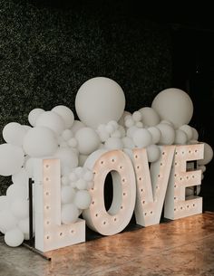 the word love spelled out in front of balloons on display at a wedding or event