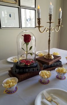 a table topped with plates and cups filled with food next to a candle holder on top of a book