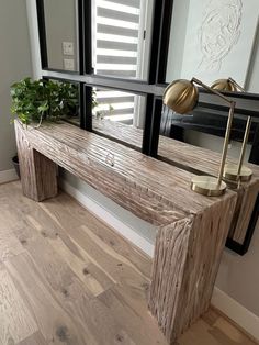 a wooden bench sitting in front of a mirror on top of a hard wood floor