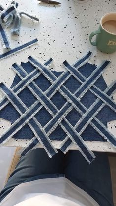 a table topped with blue and white pieces of cloth next to a cup of coffee