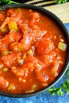 a bowl filled with stew and vegetables on top of a blue cloth next to some parsley