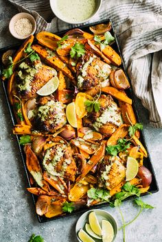 sheet pan thai roast chicken and cilantro sauce on a platter with lemon wedges