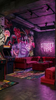 a room with couches, arcade machines and graffiti on the walls