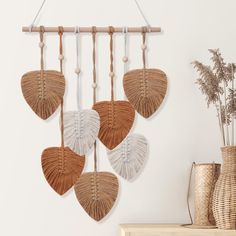 four fan shaped wall hangings on a white wall next to a vase with dried flowers