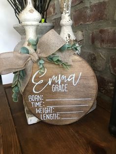 a wooden sign sitting on top of a table next to a vase filled with flowers