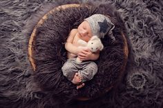 a baby sleeping in a basket with a stuffed animal