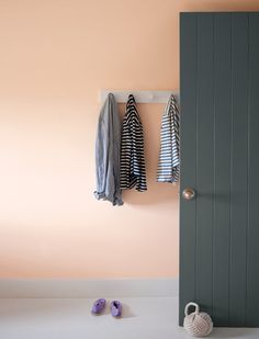 an open door with two coats hanging on the hooks and one pair of shoes next to it