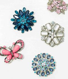 four different colored brooches on a white surface with blue, pink and green accents