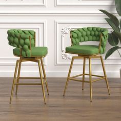 two green chairs sitting next to each other on top of a wooden floor in front of a white wall