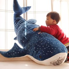 a little boy sitting on top of a stuffed whale