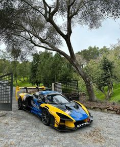 two sports cars parked next to each other in front of a gated area with trees