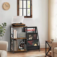 a laptop computer sitting on top of a book shelf in a living room next to a window