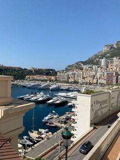 boats are docked in the water next to a large city with mountains and buildings behind them