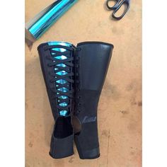 a pair of black boots sitting on top of a table next to scissors and a pen