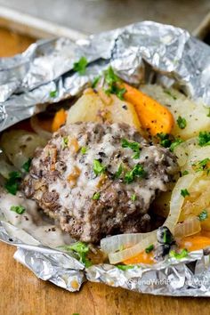 some food is wrapped in tin foil on a wooden table and ready to be eaten