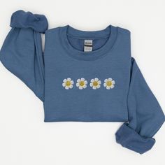 a blue sweatshirt with daisies on the front and back, sitting against a white background