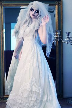 a woman in a white wedding dress and veil posing for a photo with a mirror behind her