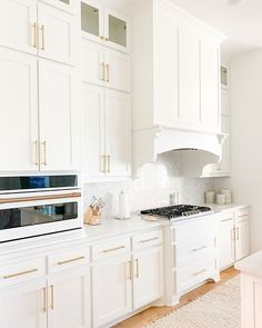 a kitchen with white cabinets and gold trim on the stove top, along with an area rug