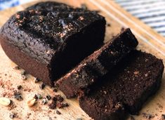 two pieces of chocolate cake sitting on top of a wooden cutting board next to nuts