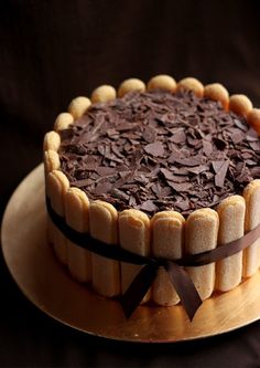 a cake with chocolate frosting sitting on top of a wooden plate