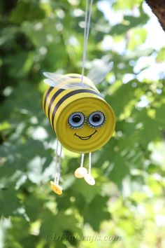 a yellow and black bee wind chime hanging from a tree