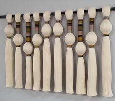 a number of wooden spoons hanging on a wall with tassels attached to them