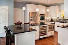 a kitchen with white cabinets and black counter tops