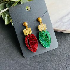 These Festive Red And Green Christmas Light Earrings Are Crafted From Glitter Acrylic, Giving Them A Fun, Sparkly Finish Perfect For The Holiday Season. Each Earring Resembles A Classic Christmas Light Bulb, With One In Red And The Other In Green For A Playful, Mismatched Design. The Acrylic Catches The Light, Adding A Cheerful Sparkle To Your Look. They Are Securely Attached To Stainless Steel Studs, Making Them Hypoallergenic And Durable For Comfortable, Long-Lasting Wear. These Earrings Are A Festive Gold Glitter Jewelry, Red Glitter Earrings For Gift, Glitter Red Earrings For Gifts, Red Glitter Earrings For Party, Red Glitter Jewelry For Party, Red Glitter Party Earrings, Christmas Party Jewelry With Sparkling Details, Sparkling Jewelry For Christmas Party, Sparkling Christmas Party Jewelry