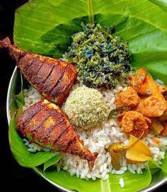 a plate filled with rice, meat and vegetables on top of a leafy plant