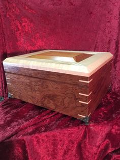 a large wooden box sitting on top of a red velvet covered table cloth with the lid open