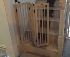 a baby gate sitting in the corner of a room next to a stair case and window