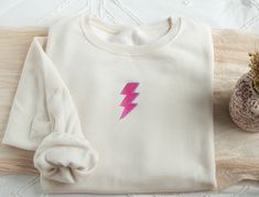 Embroidered Lightning Bolt Sweatshirt Stay cozy and fun with our uniquely embroidered sweatshirt! Made with love and THOUSANDS of threads! -Unisex Size (Please see the size chart for more details that can be found in the photos section)  We recommend comparing your favorite sweatshirt to our size chart to find the best size for you! Unisex Crewneck -50% cotton 50% polyester -Super soft -Pre-shrunk -Unisex -Design size is 3''-4"  Thread: We use the best quality threads for our embroidery designs. Pink Crew Neck Sweatshirt With Machine Embroidery, White Crew Neck Top With Embroidered Patch, White Embroidered Patch Crew Neck Top, Trendy Crewneck, Funny Gifts For Her, Sweatshirts For Women, Cute Sweatshirts, Embroidered Sweatshirt, Lightning Bolt