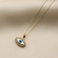 Our evil eye necklace features a 14K solid gold evil eye pendant surrounded by a halo of cubic zirconia stones and enamel detail. The necklace comes with a dainty gold chain. Gold KT: 14K Solid Gold Gold Color: Yellow Gold Pendant Height: 10mm Pendant Width: 15mm Chain Style: Rolo Chain Length: 16", 18" Chain Width: 1 mm Symbolic Gold Evil Eye Charm Necklaces, Gold Evil Eye Symbolic Necklace, Symbolic Evil Eye Pendant Jewelry, Gold Boxing Gloves, Yellow Gold Evil Eye Pendant Necklace, Minimal Gold Jewelry, Gold Plated Evil Eye Amulet Necklace, Gold Jewellry, Gold Earrings Designs