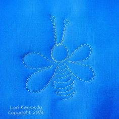 a blue piece of cloth with a bee embroidered on it