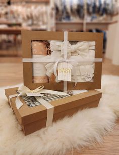 the baby shower gift set is in a brown box with white ribbon and bows on it