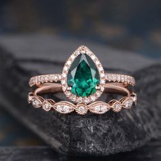 an engagement ring with a pear shaped green stone surrounded by diamonds