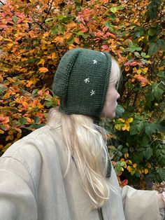 a woman wearing a green knitted hat and holding a cell phone in her hand