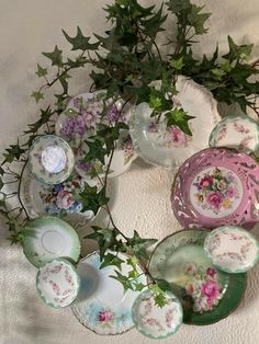 a wreath made out of plates and flowers on a tablecloth with ivy sprouting from the top