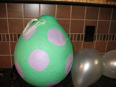 some balloons are sitting on the ground next to a green and pink polka dot egg