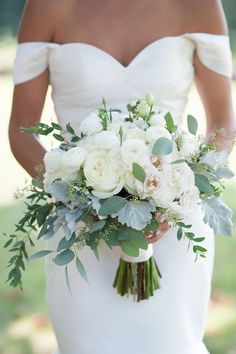 a bride holding a bouquet of white flowers