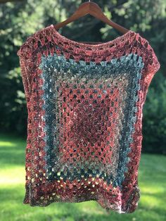 a crocheted shawl hanging on a clothesline in front of some trees