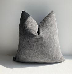 a gray pillow sitting on top of a white table