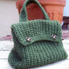 a green handbag sitting on top of a wooden table next to a potted plant